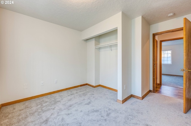 unfurnished bedroom with a closet, a textured ceiling, and light carpet