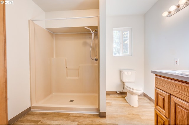 bathroom featuring hardwood / wood-style floors, vanity, toilet, and a shower