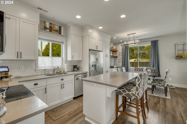 kitchen featuring pendant lighting, a kitchen island, a healthy amount of sunlight, and appliances with stainless steel finishes