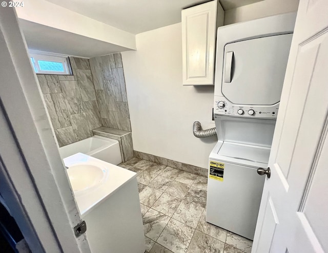 bathroom with stacked washer / drying machine, a tile shower, and vanity