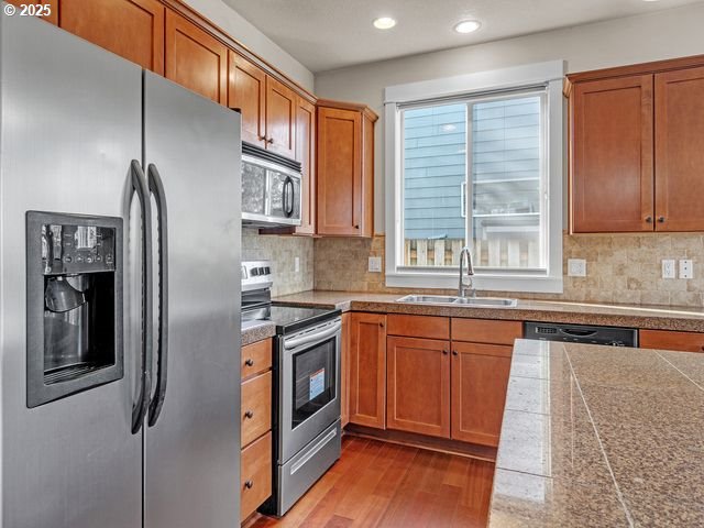 kitchen featuring sink, light wood-type flooring, tasteful backsplash, and appliances with stainless steel finishes