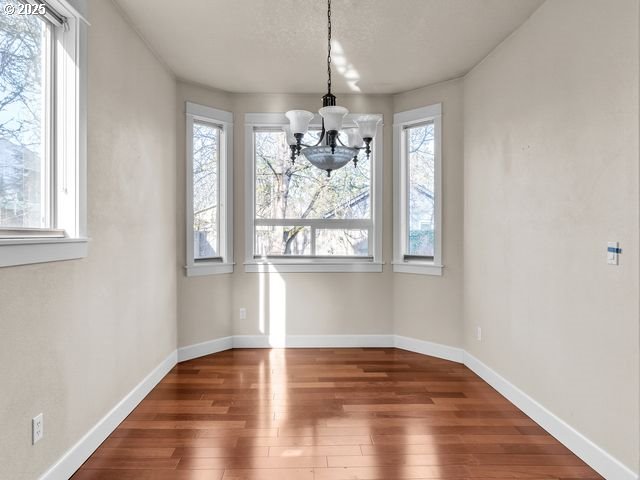 unfurnished dining area with dark wood-type flooring and a chandelier