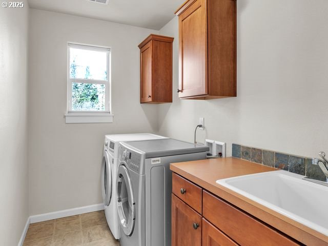 washroom with cabinets, separate washer and dryer, and sink