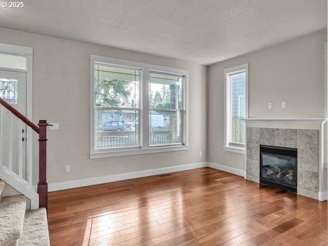 unfurnished living room featuring hardwood / wood-style flooring and a tiled fireplace