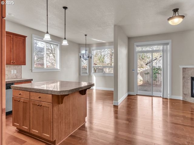 kitchen with decorative light fixtures, a fireplace, a kitchen island, decorative backsplash, and a breakfast bar area