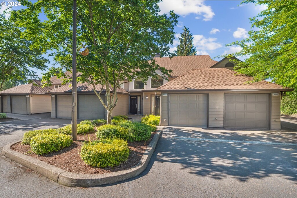 view of front of house featuring a garage, a shingled roof, and driveway