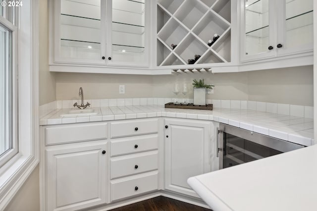 kitchen featuring sink, dark hardwood / wood-style flooring, tile counters, and white cabinets