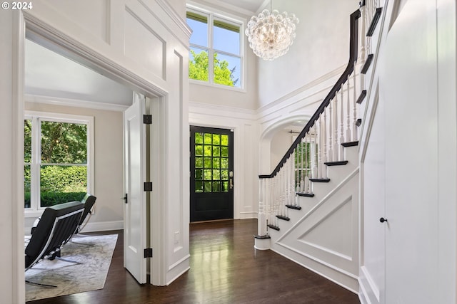 entrance foyer with a towering ceiling, dark hardwood / wood-style floors, and a chandelier