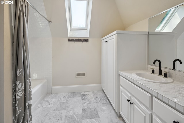 bathroom with shower / bath combo with shower curtain, tile patterned floors, vaulted ceiling with skylight, and vanity