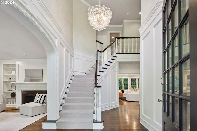 entrance foyer featuring ornamental molding, wood-type flooring, a high ceiling, and a chandelier