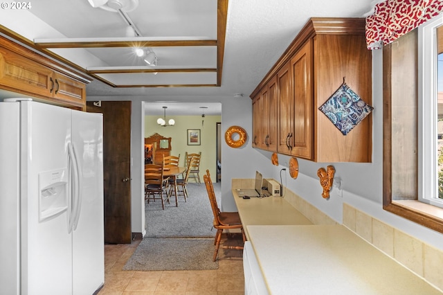 kitchen featuring light colored carpet, hanging light fixtures, and white refrigerator with ice dispenser