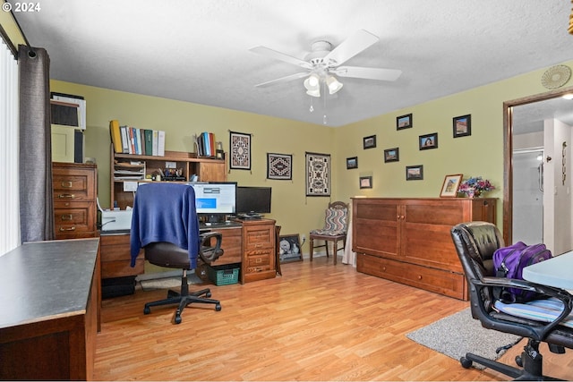 home office with ceiling fan, light hardwood / wood-style floors, and a textured ceiling