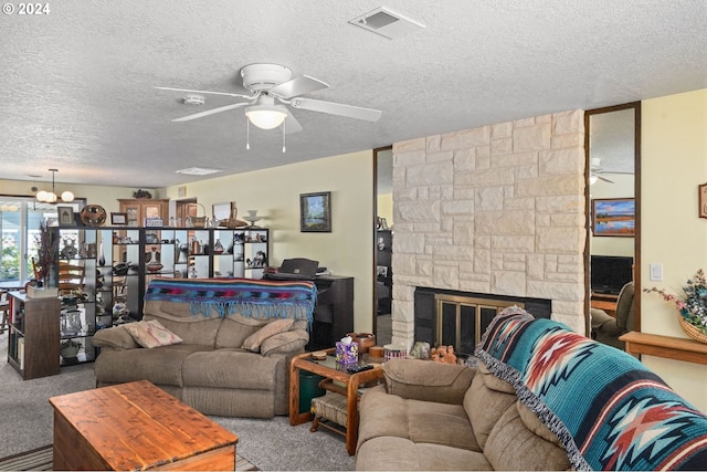 carpeted living room featuring a textured ceiling, a stone fireplace, and ceiling fan