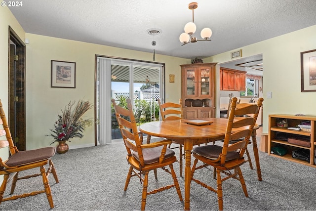 carpeted dining room featuring a chandelier and a textured ceiling