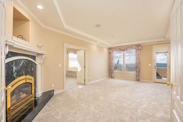 unfurnished living room with ornamental molding, a raised ceiling, carpet flooring, and a high end fireplace