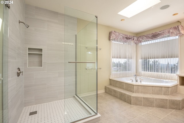 bathroom with a garden tub, a skylight, a shower stall, and tile patterned flooring