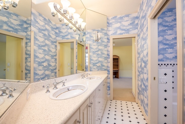 full bathroom with double vanity, wallpapered walls, and a sink