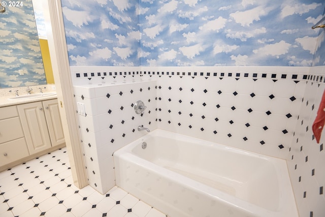 full bathroom with wallpapered walls, a bathing tub, a sink, and wainscoting