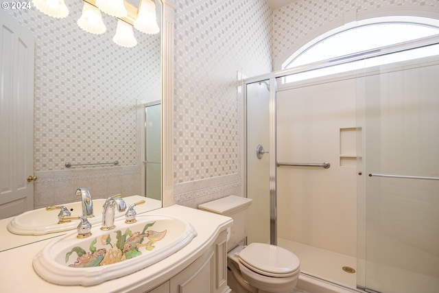 bathroom featuring toilet, wallpapered walls, vanity, and a stall shower