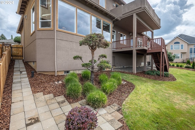 rear view of house featuring stairs, a yard, fence, and stucco siding