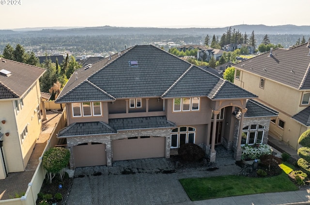 view of front facade with decorative driveway, stucco siding, an attached garage, a mountain view, and a tiled roof