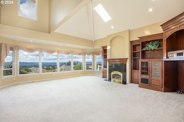 unfurnished living room with a skylight, carpet, recessed lighting, a tiled fireplace, and high vaulted ceiling