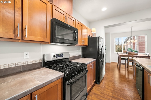 kitchen featuring a chandelier, pendant lighting, dark hardwood / wood-style floors, and black appliances