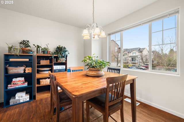 dining area with dark hardwood / wood-style floors and an inviting chandelier