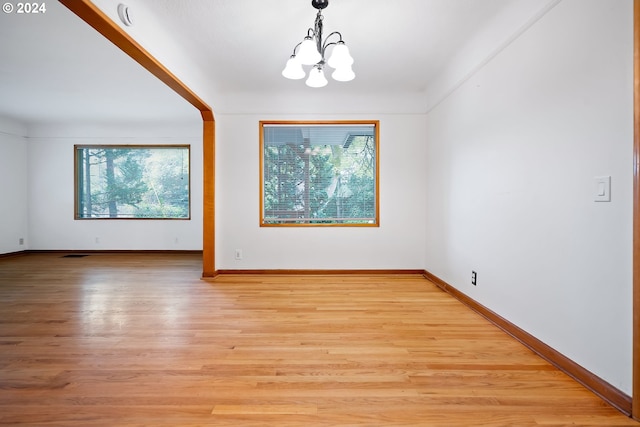 spare room featuring a chandelier and light hardwood / wood-style flooring