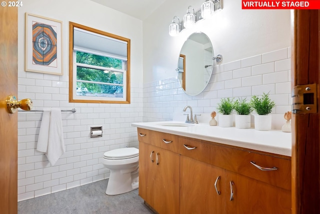 bathroom featuring vanity, toilet, and tile walls