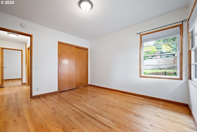 unfurnished bedroom featuring ornamental molding, light hardwood / wood-style floors, and a closet