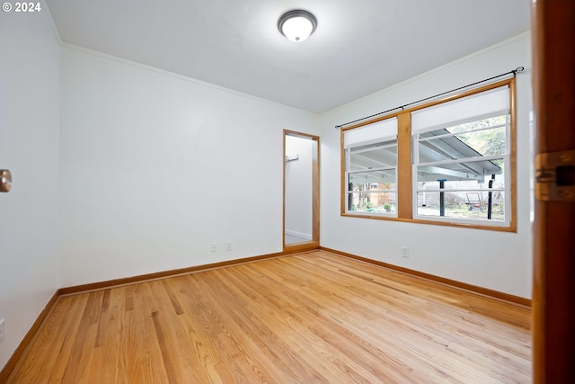 unfurnished room with ornamental molding and light wood-type flooring