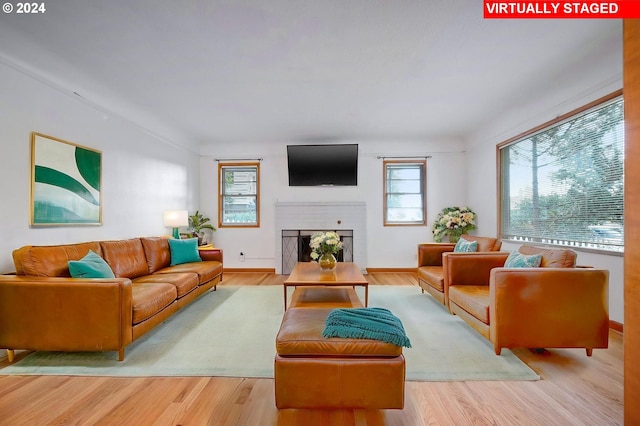 living room featuring light hardwood / wood-style flooring and a brick fireplace