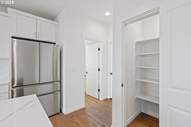 11116 NE 91st Ave, Vancouver, WA 98662 - kitchen featuring light stone countertops, light wood-style floors, freestanding refrigerator, white cabinetry, and baseboards