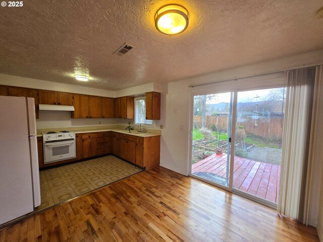 kitchen featuring a textured ceiling, white appliances, and sink