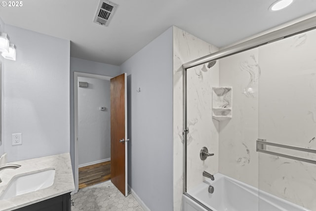 bathroom featuring visible vents, shower / bath combination with glass door, vanity, and baseboards