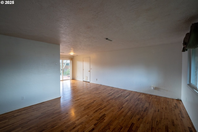 unfurnished room featuring visible vents, a textured ceiling, and wood finished floors