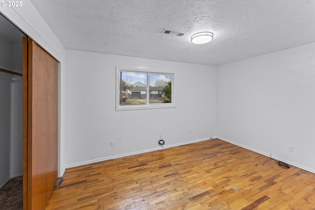 unfurnished bedroom featuring wood-type flooring, a textured ceiling, and a closet