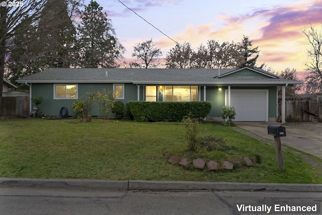 ranch-style house featuring concrete driveway, a lawn, an attached garage, and fence