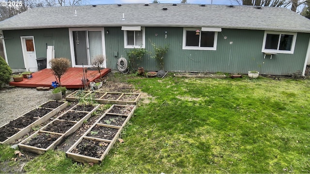 back of property with a vegetable garden, a lawn, and roof with shingles