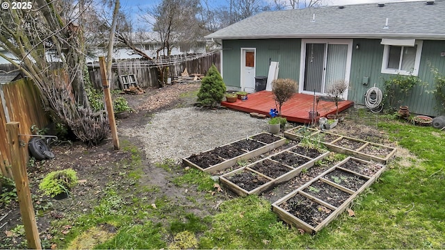 view of yard featuring a deck, a garden, and a fenced backyard