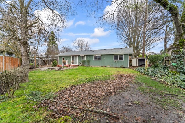 rear view of house with an outbuilding, a storage unit, a lawn, and a fenced backyard