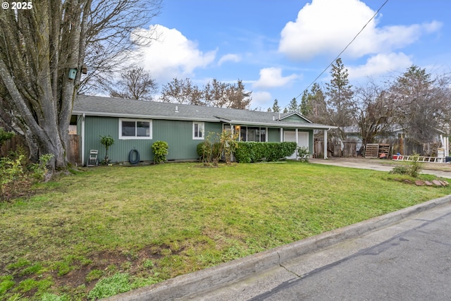 ranch-style home featuring a front yard, concrete driveway, fence, and an attached garage