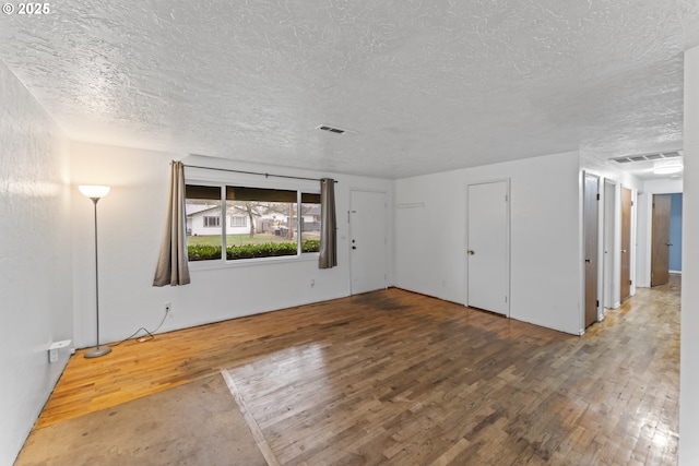 unfurnished room with wood-type flooring and a textured ceiling