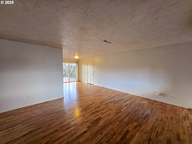 spare room featuring visible vents, a textured ceiling, and wood finished floors