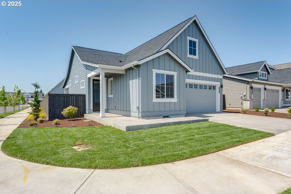 1819 S Maple St, Canby, OR 97013 - view of front facade with board and batten siding, driveway, a front lawn, and roof with shingles