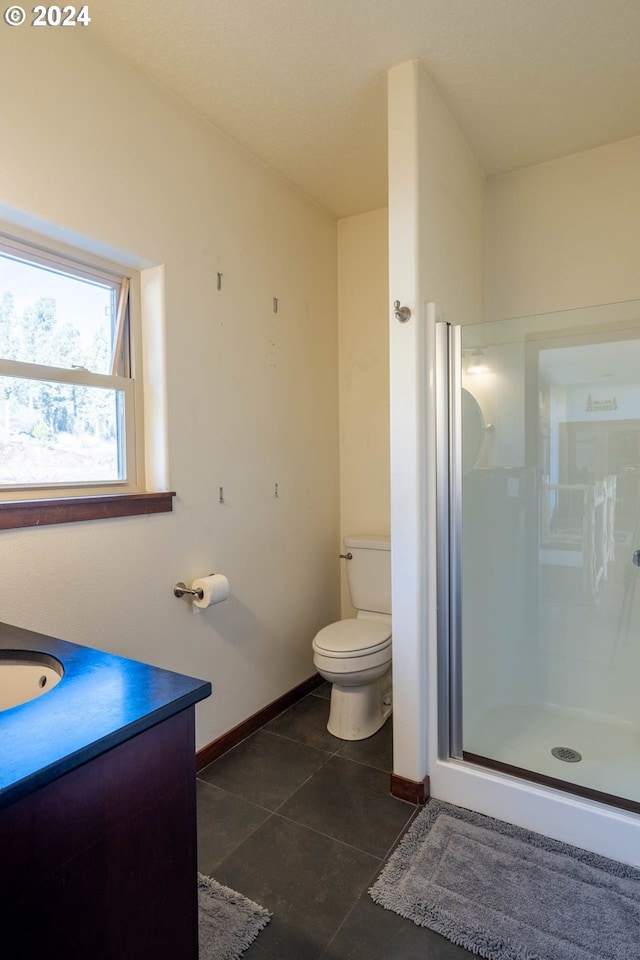 bathroom featuring toilet, vanity, tile patterned floors, and a shower with door