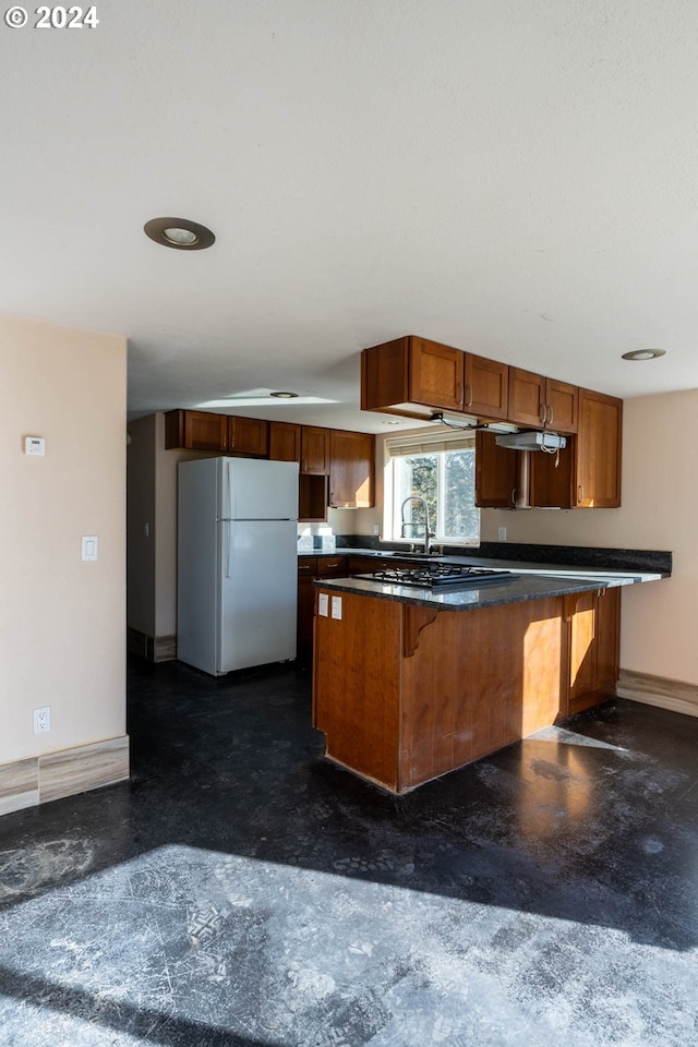 31367 Clarks Creek Rd, Mount Vernon, OR 97865 - kitchen featuring freestanding refrigerator, baseboards, dark countertops, brown cabinetry, and a kitchen breakfast bar