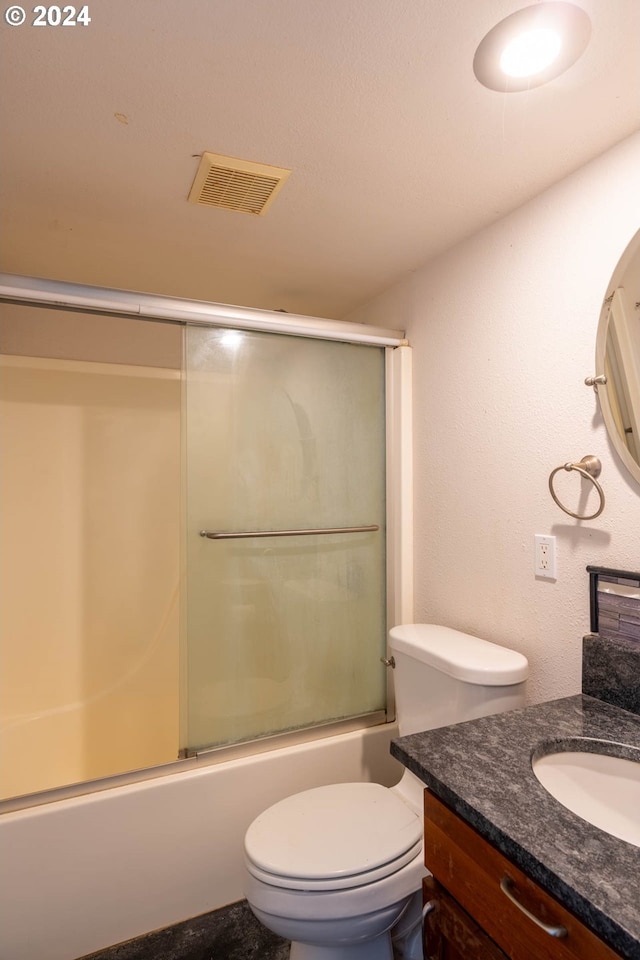 full bathroom with combined bath / shower with glass door, vanity, and toilet