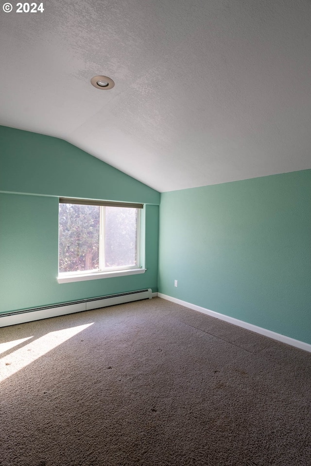 spare room featuring a baseboard heating unit, carpet, lofted ceiling, and a textured ceiling